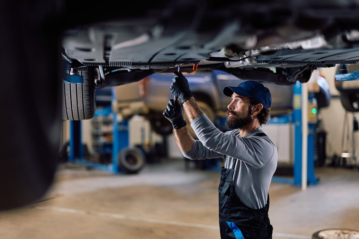 Auto repairman doing maintenance on a chassis while working in a garage