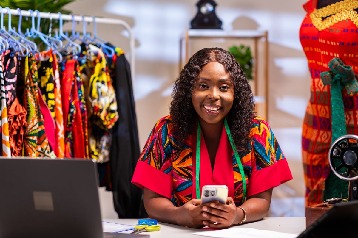 Small business owner smiling while using her smartphone in her workshop